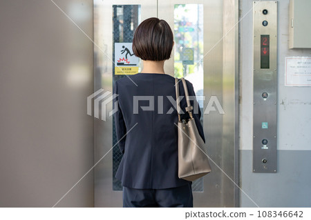 A woman riding an elevator 108346642