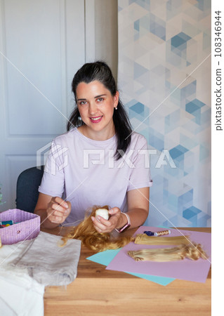 Creative young adult woman making handmade doll. 108346944