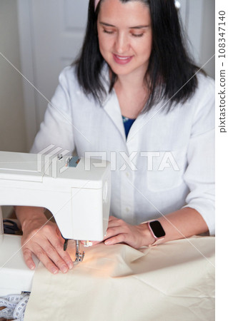 Young adult seamstress working on sewing machine. 108347140