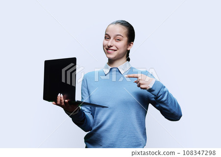 Teenage girl student using laptop, on white background, pointing at screen 108347298