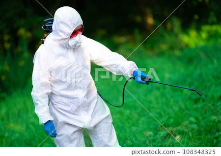 A worker sprays pesticides on trees outdoors. Tree pest control. Insect pest control 108348325