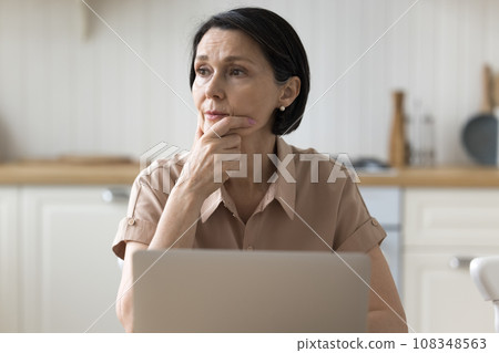 Brooding woman deep in thought sit at table with laptop Brooding woman deep in thought sit at table with laptop 108348563