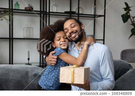 Peaceful daddy hugging little preteen daughter girl holding surprise gift 108348809