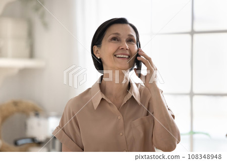 Happy attractive aged woman enjoy conversation on cellphone 108348948