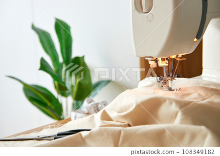 Sewing machine with piece of beige fabric. 108349182
