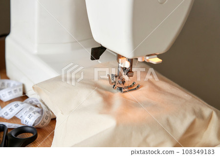 Sewing machine with piece of beige fabric. 108349183