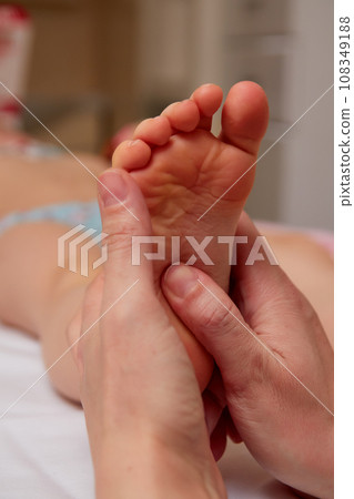Doctor performing pediatric foot massage to prevent development of flat feet Doctor performing pediatric foot massage to prevent development of flat feet 108349188
