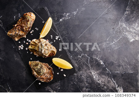 Fresh closed oysters with lemon on slate plate 108349374