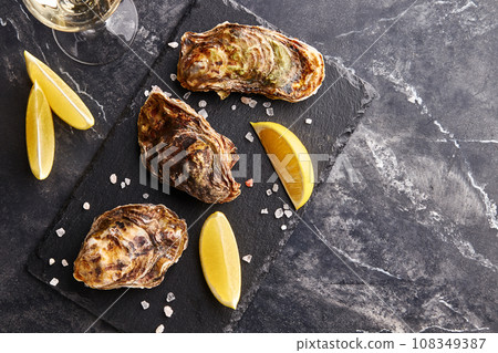 Fresh closed oysters with lemon on slate plate 108349387