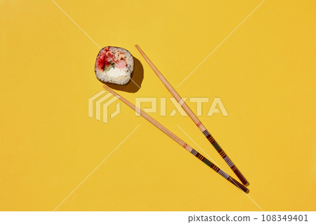 Fresh sushi roll and chopsticks on yellow background. 108349401
