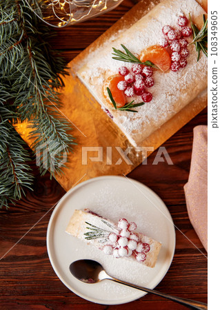 Slice of meringue roll with cherries decorated for Christmas. Slice of meringue roll with cherries decorated for Christmas. 108349605