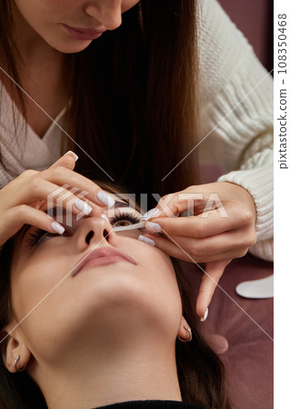 master preparing glue cotton tape under eye before eyelash extension procedure 108350468