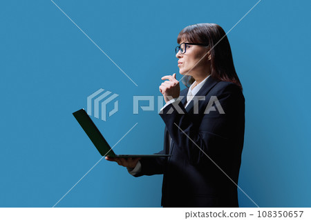 Serious mature business woman using laptop, on blue background 108350657