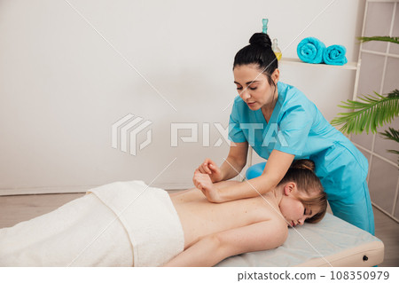 a woman massages a client in a massage room training spa healthy back 108350979