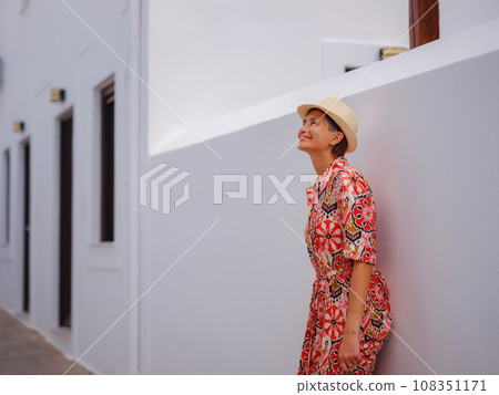 Nice asian Happy Female in boho dress Enjoying Sunny Day on Greek Islands. Travel to Lindos, Mediterranean islands outside tourist season. Tourist woman on vacation in Greece walking through the Nice asian Happy Female in boho dress Enjoying Sunny Day on Greek Islands. Travel to Lindos, Mediterranean islands outside tourist season. Tourist woman on vacation in Greece walking through the 108351171