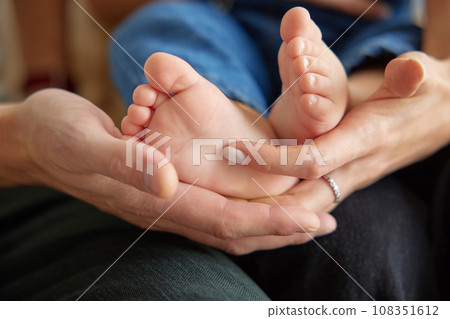 Close up view of baby feet. Mother touching her small child's toes while he is asleep. Baby toe. Newborn close up photography. Tiny beautiful baby's feet.  108351612