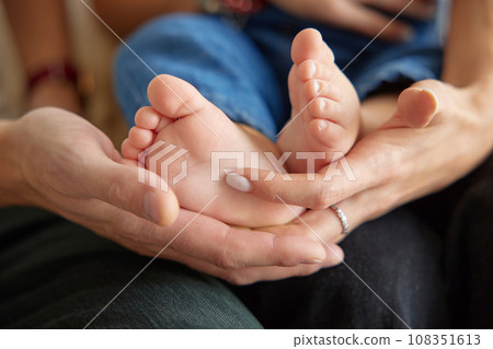 Close up view of baby feet. Mother touching her small child's toes while he is asleep. Baby toe. Newborn close up photography. Tiny beautiful baby's feet.  108351613