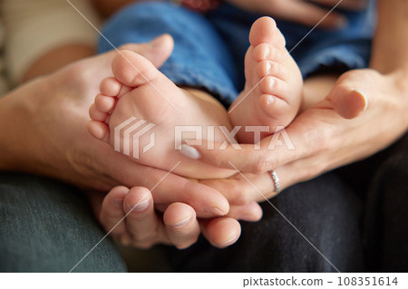 Close up view of baby feet. Mother touching her small child's toes while he is asleep. Baby toe. Newborn close up photography. Tiny beautiful baby's feet.  108351614