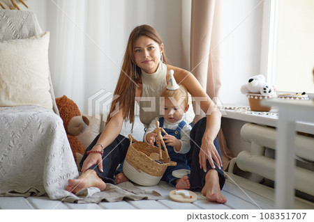 Unconditional love. Happy young mother enjoying time with her adorable toddler son at home, lifting him in the air, playing with kid boy in living room, free space Unconditional love. Happy young mother enjoying time with her adorable toddler son at home, lifting him in the air, playing with kid boy in living room, free space 108351707