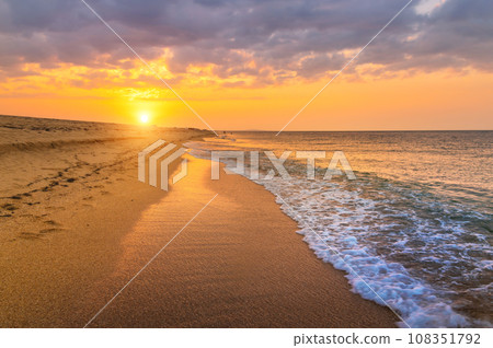 Amazing beach sunset with incredible foamy waves, and cloudy dramatic sky. There's no one on the beach 108351792
