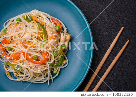 Tasty dish of Asian cuisine with rice noodles, chicken, asparagus, pepper, sesame seeds 108352120