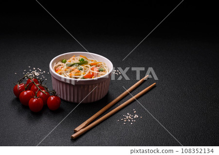 Tasty dish of Asian cuisine with rice noodles, chicken, asparagus, pepper, sesame seeds 108352134