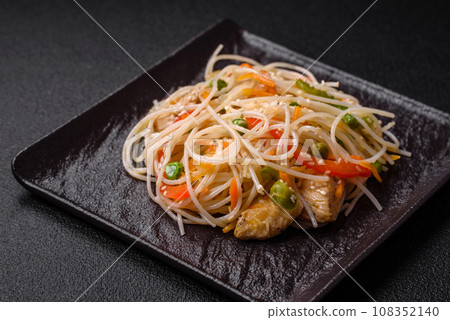 Tasty dish of Asian cuisine with rice noodles, chicken, asparagus, pepper, sesame seeds 108352140