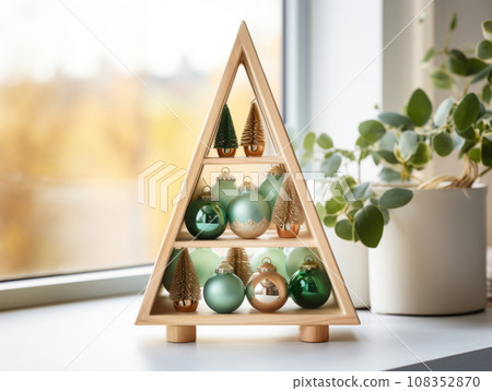 Handmade Christmas decor. Stand in the shape of a Christmas tree with decorative holiday balls. Detail of Christmas interior on a shelf in the room. Handmade Christmas decor. Stand in the shape of a Christmas tree with decorative holiday balls. Detail of Christmas interior on a shelf in the room. 108352870