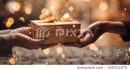 Hands of a woman with a New Year's gift box against a Christmas backdrop Hands of a woman with a New Year's gift box against a Christmas backdrop 108352879