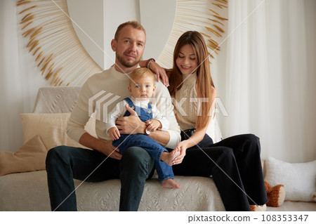 Happy family moments together. Caucasian young happy family nurturing taking care of small little kid child toddler infant baby at home. Parenthood and adoption Happy family moments together. Caucasian young happy family nurturing taking care of small little kid child toddler infant baby at home. Parenthood and adoption 108353347