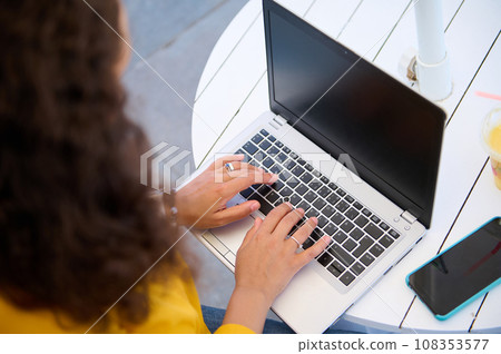 Overhead view of woman typing text on laptop keyboard, blank mockup screen, working remotely. Online Business. Education Overhead view of woman typing text on laptop keyboard, blank mockup screen, working remotely. Online Business. Education 108353577
