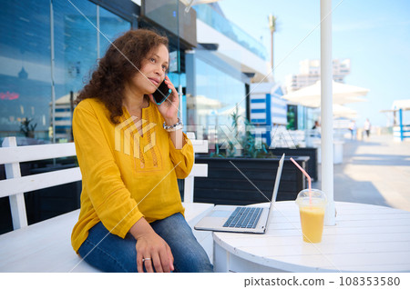 Confident businesswoman talking on smart mobile phone, negotiating with business partners, working online on laptop. Confident businesswoman talking on smart mobile phone, negotiating with business partners, working online on laptop. 108353580