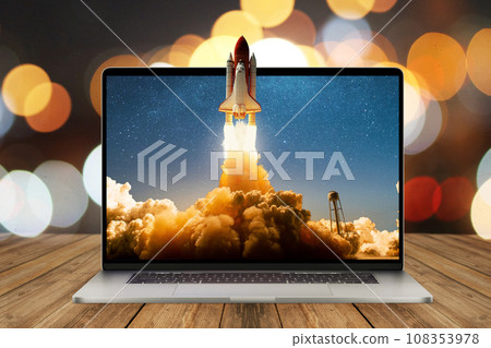 Space rocket shuttle with a cloud of smoke and blast lift off from a laptop on a working office desk with bokeh. Creative idea and startup. Successful business project. Rocket take off from display Space rocket shuttle with a cloud of smoke and blast lift off from a laptop on a working office desk with bokeh. Creative idea and startup. Successful business project. Rocket take off from display 108353978