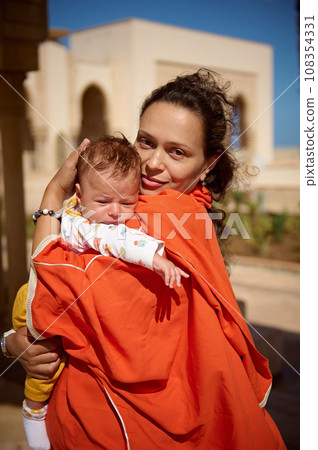 Beautiful Middle Eastern woman, loving mother in Oriental attire, holding her newborn baby boy, looking at camera Beautiful Middle Eastern woman, loving mother in Oriental attire, holding her newborn baby boy, looking at camera 108354331