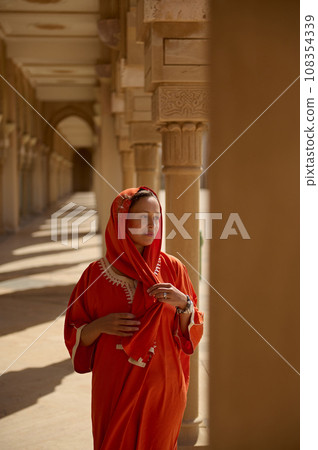 Beautiful Middle Eastern Muslim woman with head covered in hijab, walks along the marble columns in the mosque territory 108354339