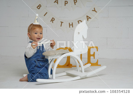 First birthday baby boy party. Happy beautiful baby of European appearance with white hair and blue eyes on white background. 108354528