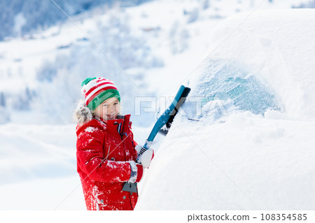 Child brushing off car. Kid with winter snow brush Child brushing off car. Kid with winter snow brush 108354585