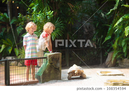 Kids feed animals at petting zoo. Kids feed animals at petting zoo. 108354594