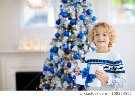 Child at Christmas tree. Kids at fireplace on Xmas Child at Christmas tree. Kids at fireplace on Xmas 108354595