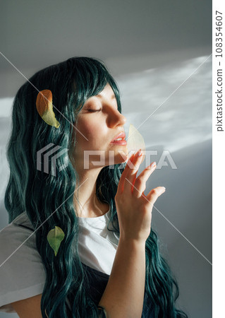 Beautiful tender girl with long dark green hair holding multicolor skeleton leaf in ray of sunset light. Attractive fantasy girl, Young elven princess style. A gentle image. Autumn, fall concept. Beautiful tender girl with long dark green hair holding multicolor skeleton leaf in ray of sunset light. Attractive fantasy girl, Young elven princess style. A gentle image. Autumn, fall concept. 108354607