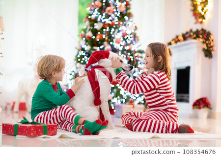 Christmas at home. Kids and dog under Xmas tree. 108354676