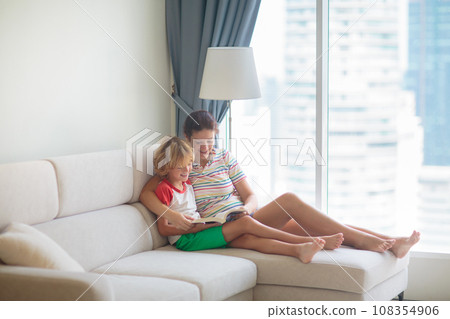 Child and mother read a book in sunny room 108354906