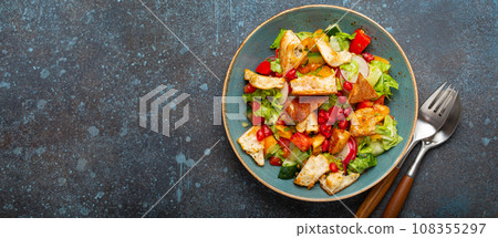 Traditional Levant dish Fattoush salad, Arab cuisine, made with pita bread croutons, vegetables and herbs. Healthy Middle Eastern vegetarian salad on plate, rustic dark blue background top view Traditional Levant dish Fattoush salad, Arab cuisine, made with pita bread croutons, vegetables and herbs. Healthy Middle Eastern vegetarian salad on plate, rustic dark blue background top view 108355297