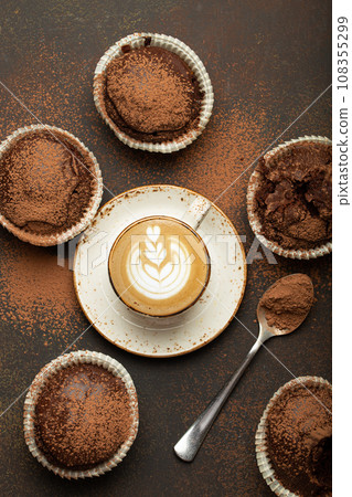 Chocolate and cocoa browny muffins with coffee cappuccino in cup top view on brown rustic stone background, sweet homemade dark chocolate cupcakes Chocolate and cocoa browny muffins with coffee cappuccino in cup top view on brown rustic stone background, sweet homemade dark chocolate cupcakes 108355299