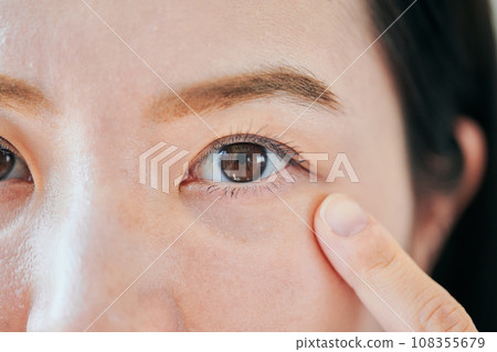 Young woman pointing to her left eye 108355679