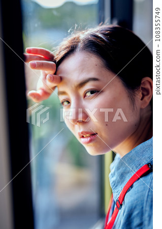 Young woman putting her hand on her head by the window Young woman putting her hand on her head by the window 108355749