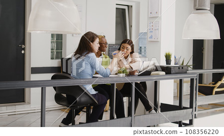 Multiethnic group of employees discussing new strategy for business development in coworking space. Professional women thinking about corporate investment to increase profit in office. 108356220