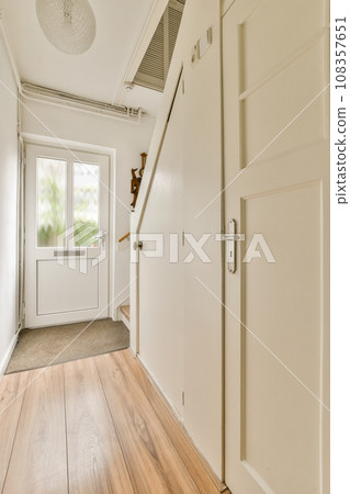 an empty room with wood flooring and white door leading you to the front door, there is a cat sitting on top of an empty room with wood flooring and white door leading you to the front door, there is a cat sitting on top of 108357651