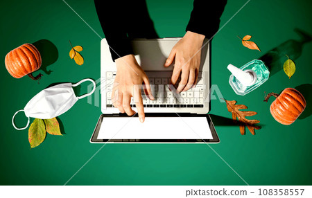 Person using a laptop computer with a mask and a sanitizer bottle Person using a laptop computer with a mask and a sanitizer bottle 108358557