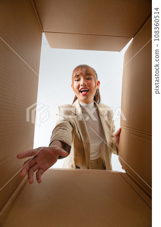 Happy excited customer opening parcel, looking inside package with shock, surprise, joy. Happy excited customer opening parcel, looking inside package with shock, surprise, joy. 108360514